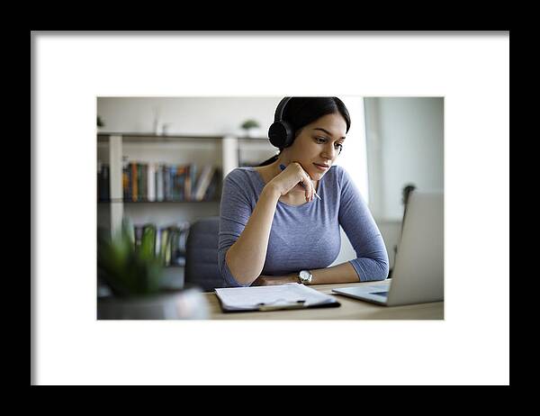 Working Framed Print featuring the photograph Young woman with headphones working from home by Damircudic