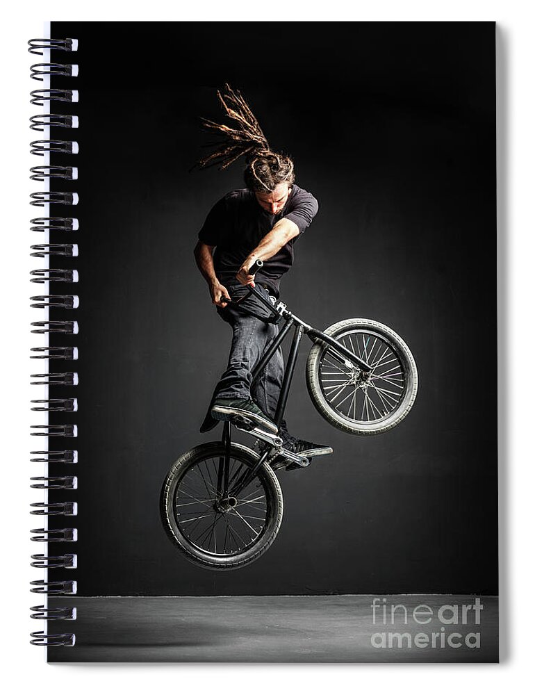 Man Spiral Notebook featuring the photograph A man doing an extreme stunt on his BMX bicycle. by Michal Bednarek