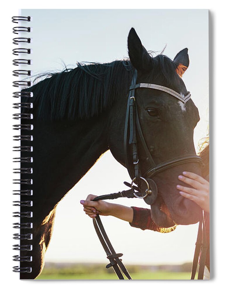 Woman Spiral Notebook featuring the photograph Attractive young woman holding a dark horse on a harness. by Michal Bednarek