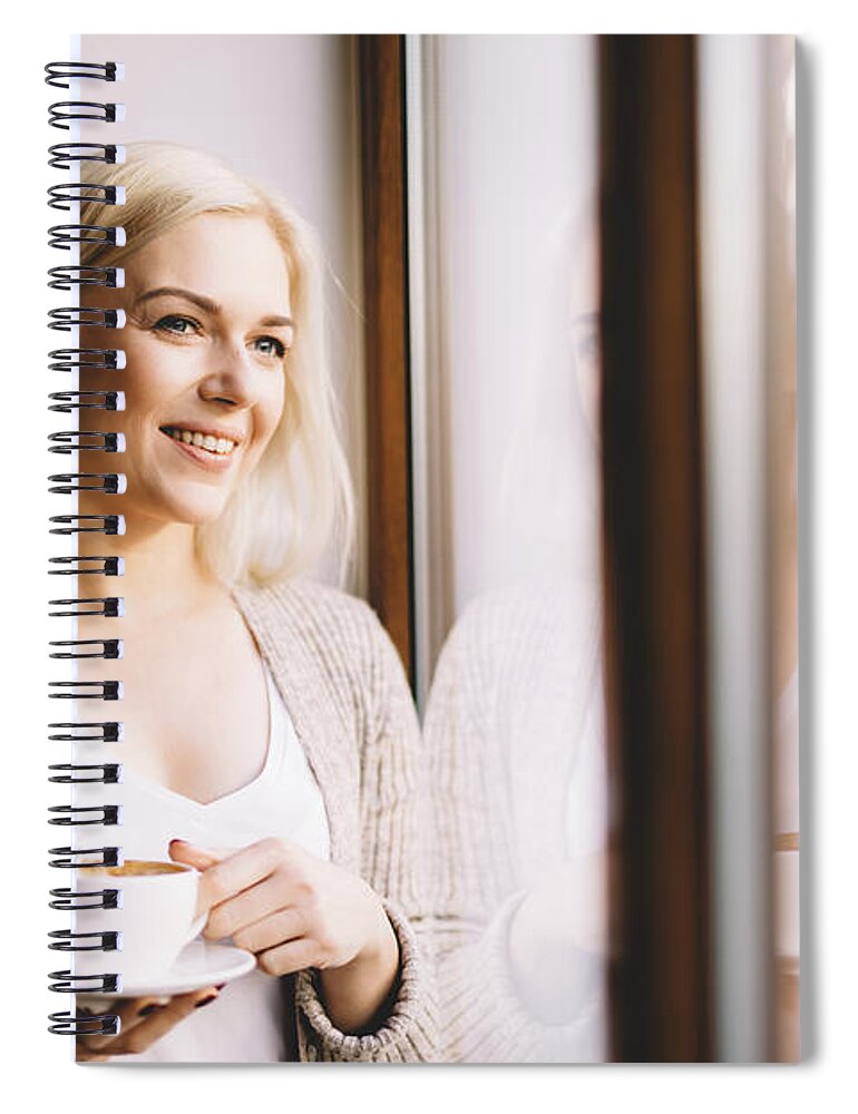 Woman Spiral Notebook featuring the photograph Woman with a cup of coffee standing by the window. by Michal Bednarek
