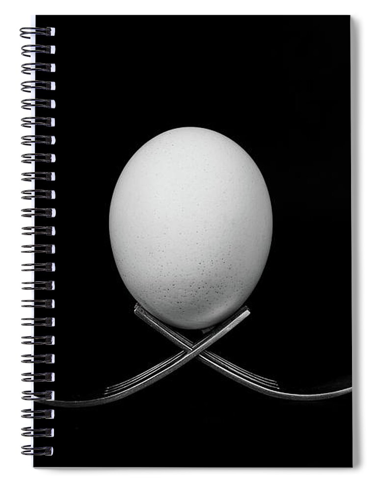 Egg Spiral Notebook featuring the photograph White egg resting on two metal and shiny forks on a black backg #1 by Michalakis Ppalis