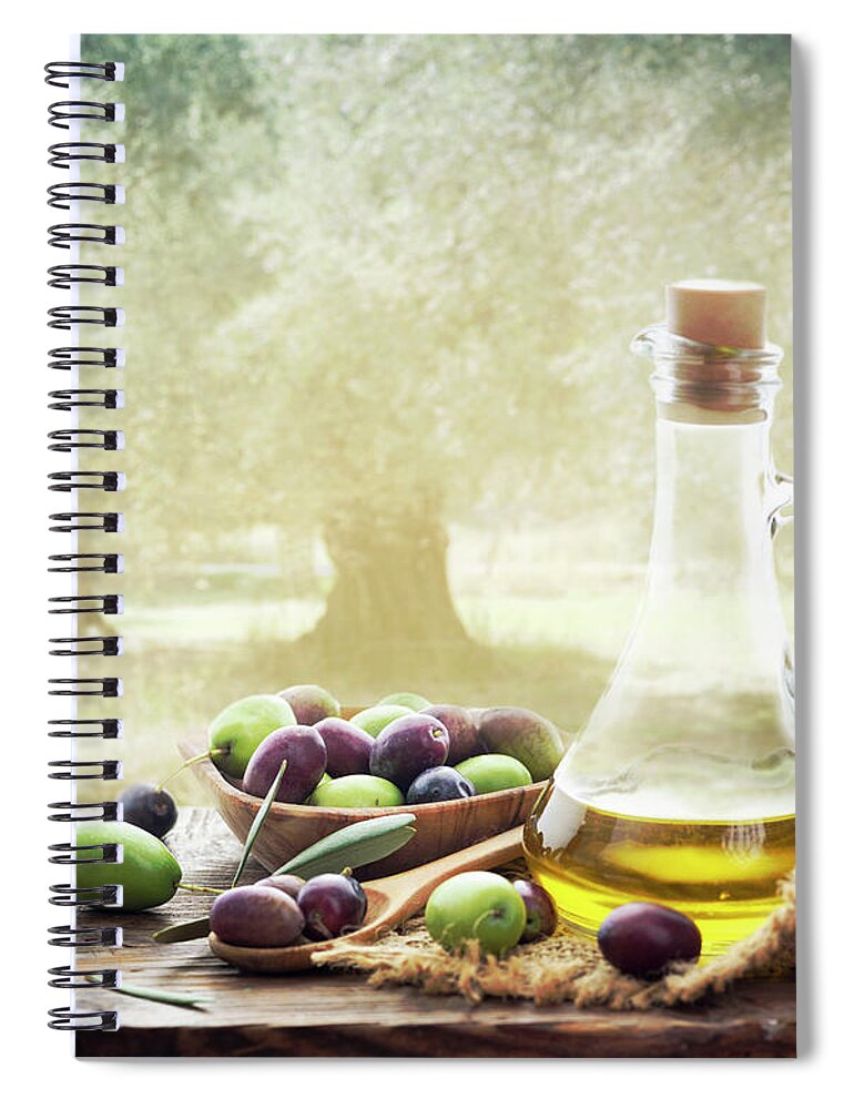 Olive Spiral Notebook featuring the photograph Olives and bottle of olive oil on wooden table in olive garden by Jelena Jovanovic