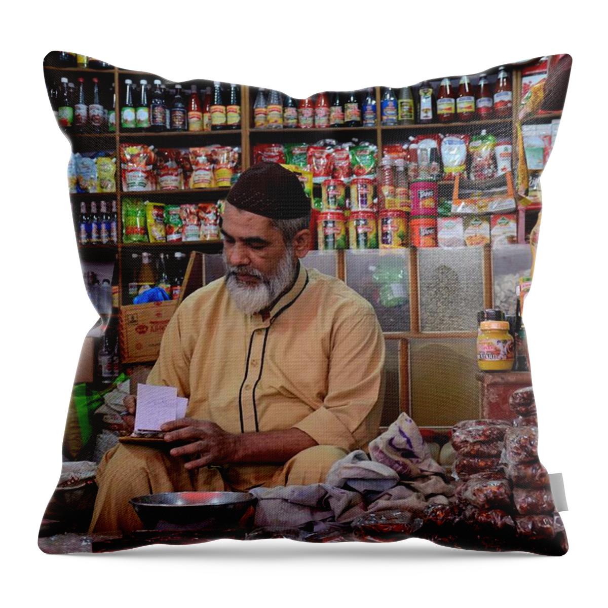 Man Throw Pillow featuring the photograph General store keeper tends to paperwork at Empress Market Karachi Pakistan by Imran Ahmed