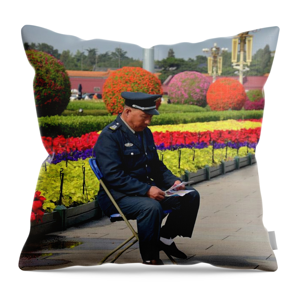 Guard Throw Pillow featuring the photograph Chinese security guard reads in front of flower display Beijing China by Imran Ahmed