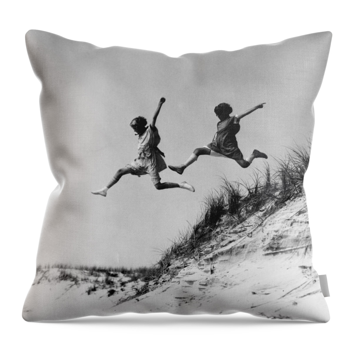 1920s Throw Pillow featuring the photograph Two Girls Leaping Off Sand Dune by H Armstrong Roberts and ClassicStock