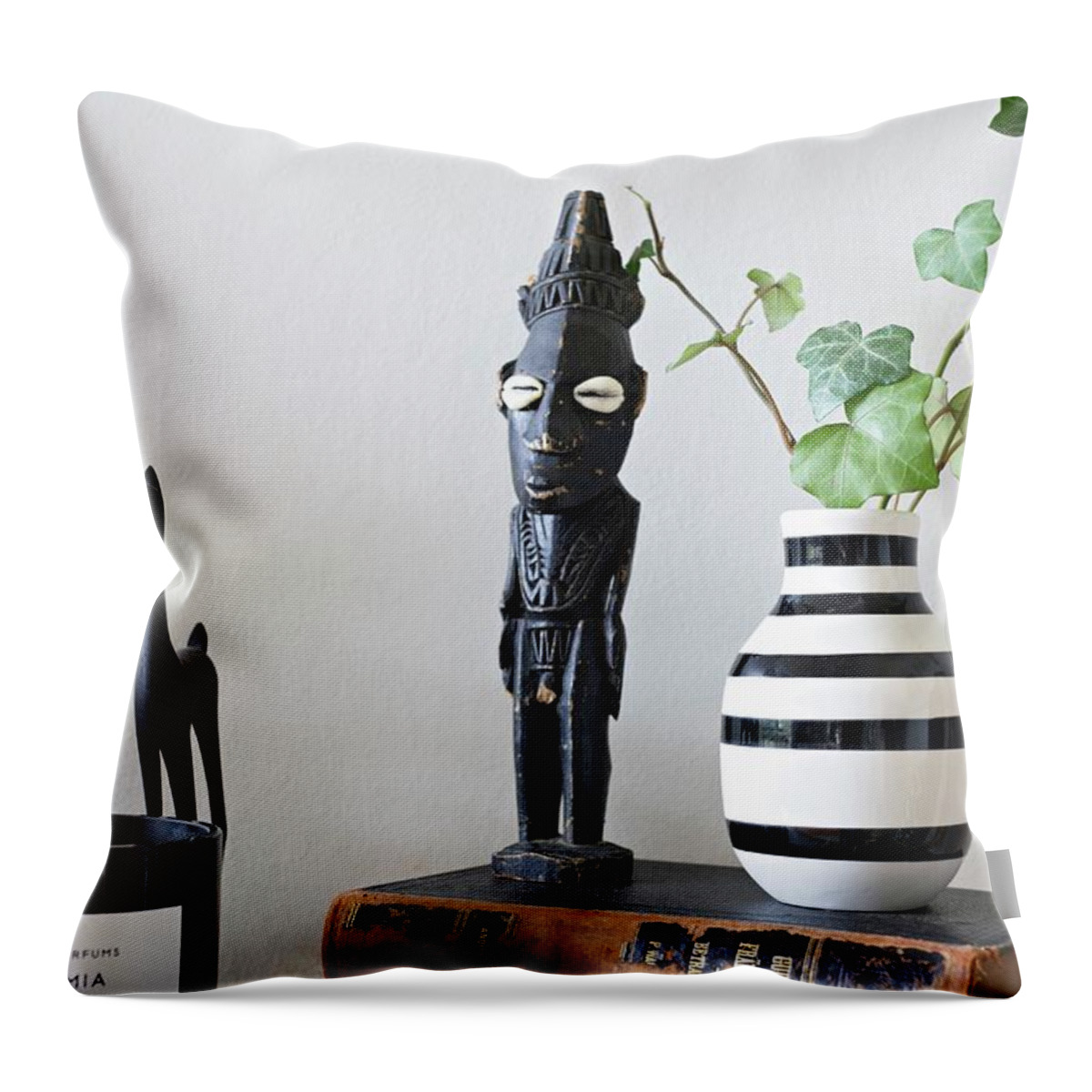 Ip_11405189 Throw Pillow featuring the photograph African Figurines And Striped Vase On Top Of Two Old Books by Cecilia Mller