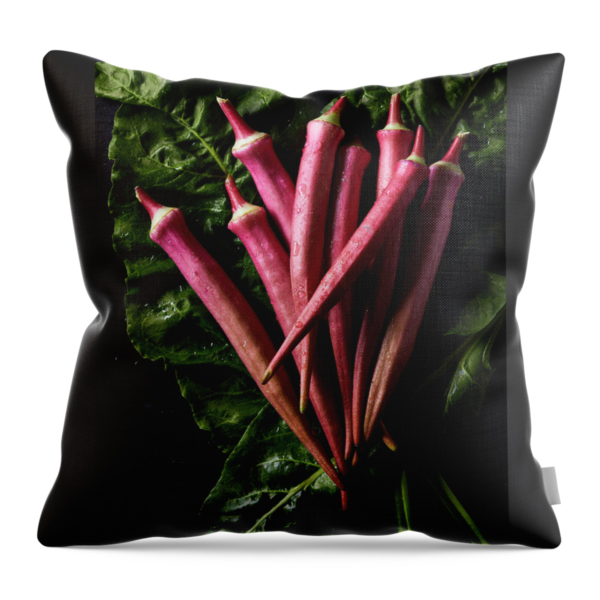 Red Okra Throw Pillow featuring the photograph Wet red okra on bed of chard by Cuisine at Home