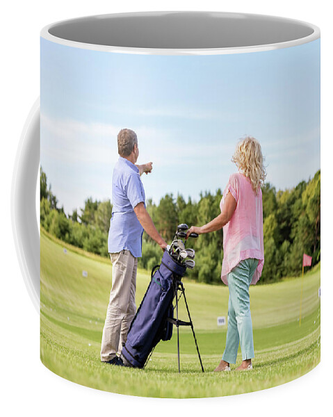 Senior Coffee Mug featuring the photograph Active senior couple playing golf on a course. #1 by Michal Bednarek