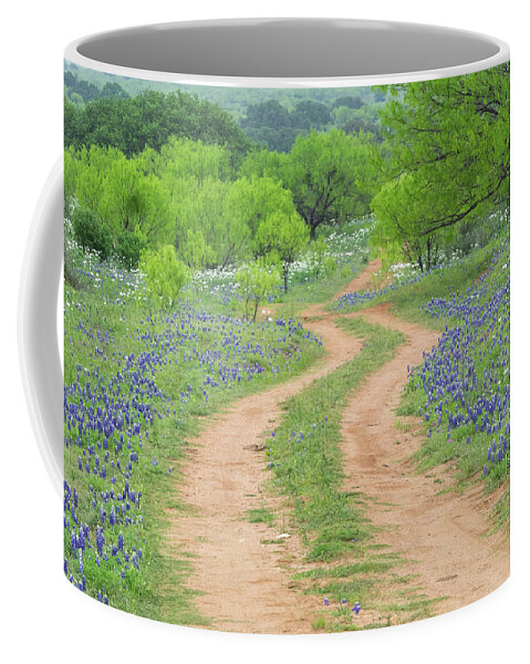 Texas Coffee Mug featuring the photograph A dirt road lined by Blue Bonnets of Texas by Usha Peddamatham