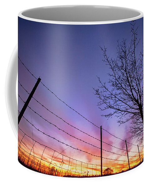 Sunset Coffee Mug featuring the photograph Fiery Norfolk sunset viewed through barbed fence by Simon Bratt