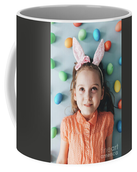 Girl Coffee Mug featuring the photograph Girl with bunny ears surrounded by colorful eggs. by Michal Bednarek