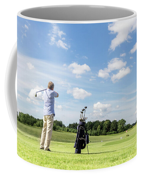 Golf Coffee Mug featuring the photograph Senior fit man hitting a golf ball. by Michal Bednarek