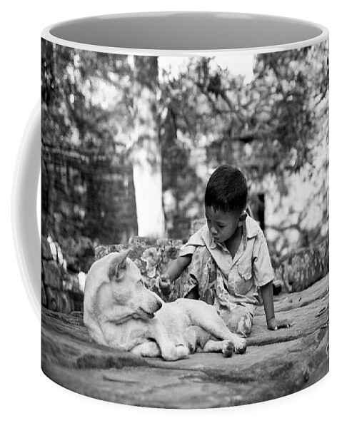 2015 Coffee Mug featuring the photograph Cambodian boy near some ruins playing with his dog. #1 by Joaquin Corbalan