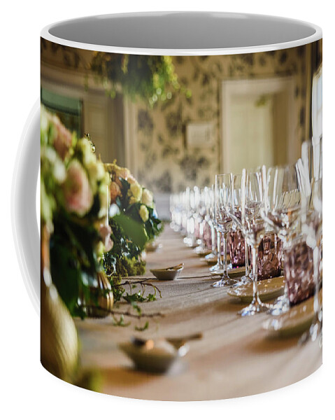 Alcohol Coffee Mug featuring the photograph Elongated table with all the cutlery elegantly arranged and beautiful centerpieces ideal for decorating a wedding. by Joaquin Corbalan