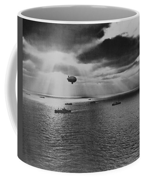 Sunset Coffee Mug featuring the painting Sunset over the Atlantic finds another United Nations convoy moving peacefully towards it destination. A U.S. Navy blimp, hovering watchfully overhead, is on the lookout for any sign of enemy submarines by 