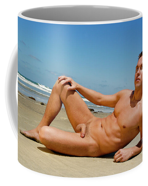 Nude Coffee Mug featuring the photograph Handsome nude and muscular man poses on the wet sand at the beach. by Gunther Allen