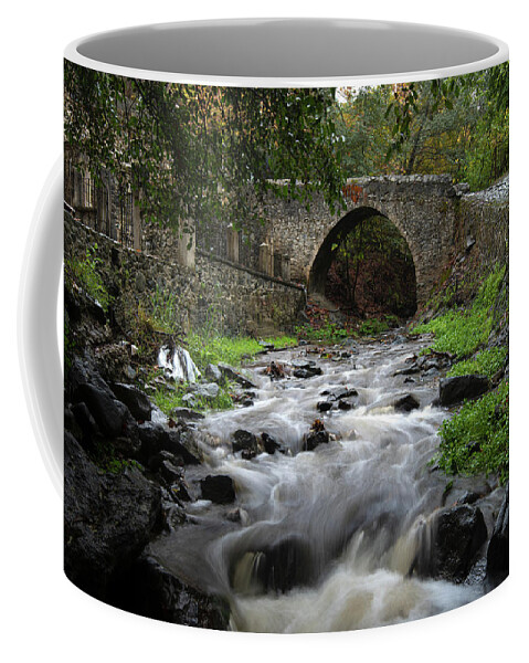 River Coffee Mug featuring the photograph Medieval stoned bridge water flowing in the river. by Michalakis Ppalis