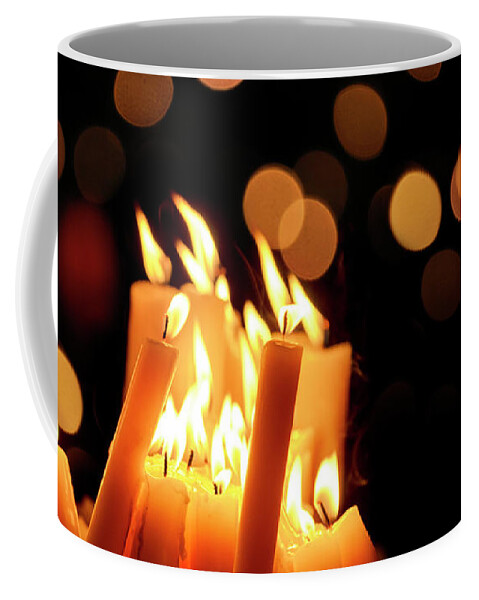 Candle Coffee Mug featuring the photograph Religious candles in front of bokeh light by Jelena Jovanovic