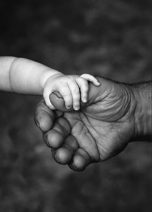 Weak And Strong Greeting Card featuring the photograph Babys Hand Holding On To Adult Hand #1 by Corey Hochachka
