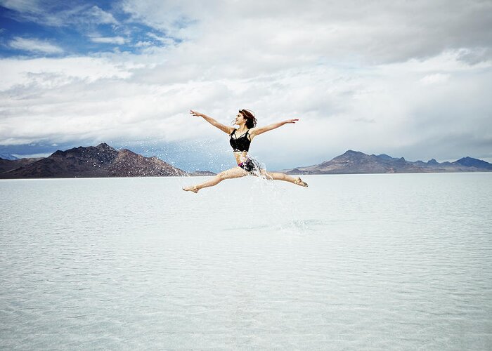 Ballet Dancer Greeting Card featuring the photograph Ballerina Leaping In Mid-air Over Lake #1 by Thomas Barwick