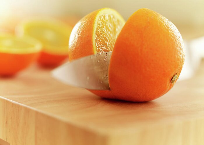 Food And Drink Greeting Card featuring the photograph Knife Slicing Orange On Cutting Board by Adam Gault