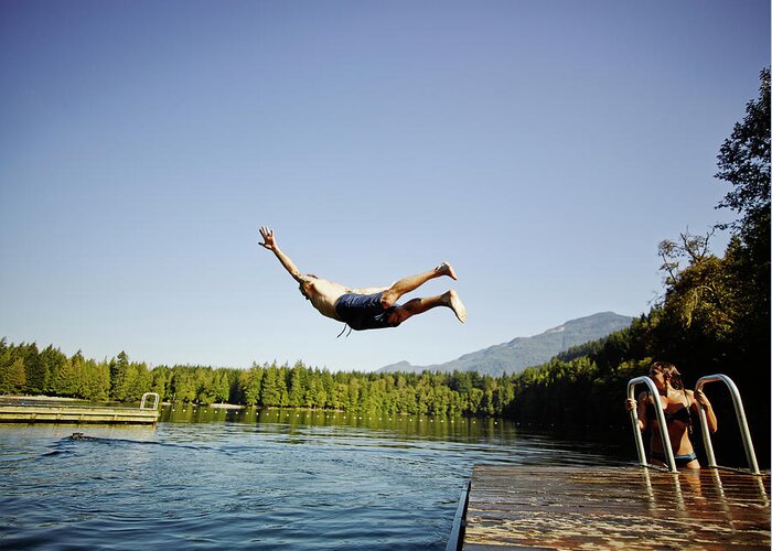 Tranquility Greeting Card featuring the photograph Man Diving Off Dock Into Mountain Lake by Thomas Barwick