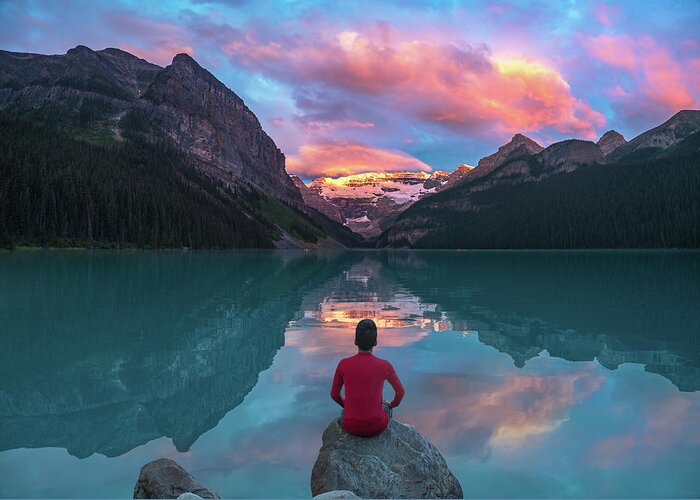 America Greeting Card featuring the photograph Man sit on rock watching Lake Louise morning clouds with reflect by William Lee