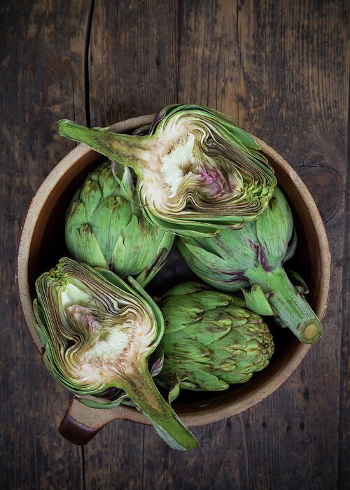 Crockery Greeting Card featuring the photograph Bowl Of Organic Artichokes On Wooden by Westend61