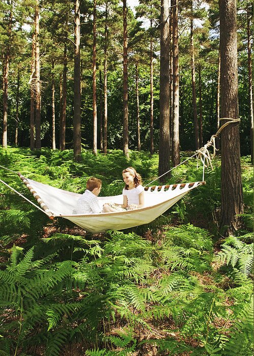 Hanging Greeting Card featuring the photograph Boy And Girl 8-10 Sitting On Hammock In by Martin Barraud