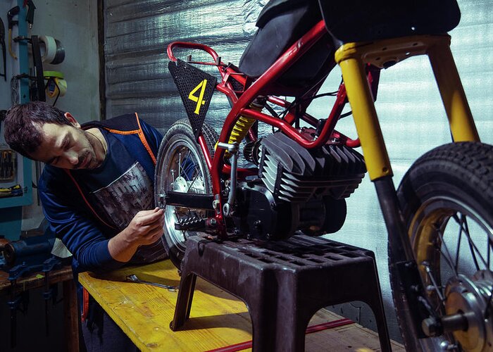 Engineer Greeting Card featuring the photograph Engineer Repairing Motorcycle At Garage by Cavan Images