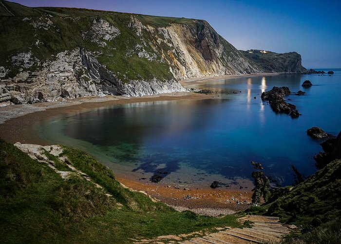 Durdle Door Greeting Card featuring the photograph Man o war bay in England seen on a clear beautiful night. by George Afostovremea