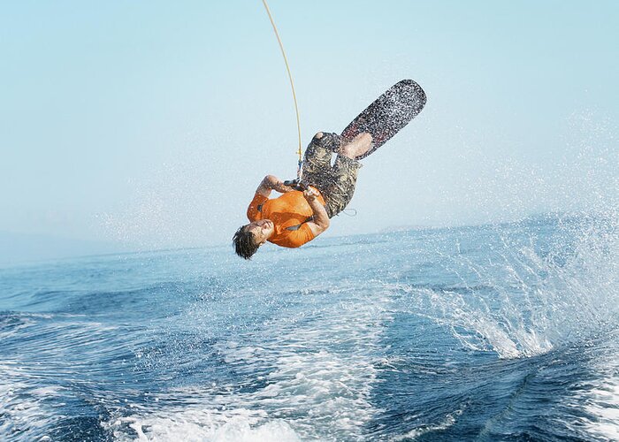 One Man Only Greeting Card featuring the photograph Man Performing Wakeboarding Stunt At Sea by Paul Bradbury