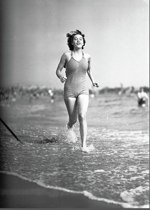 1950-1959 Greeting Card featuring the photograph Woman In Swimsuit Running On Shoreline by George Marks