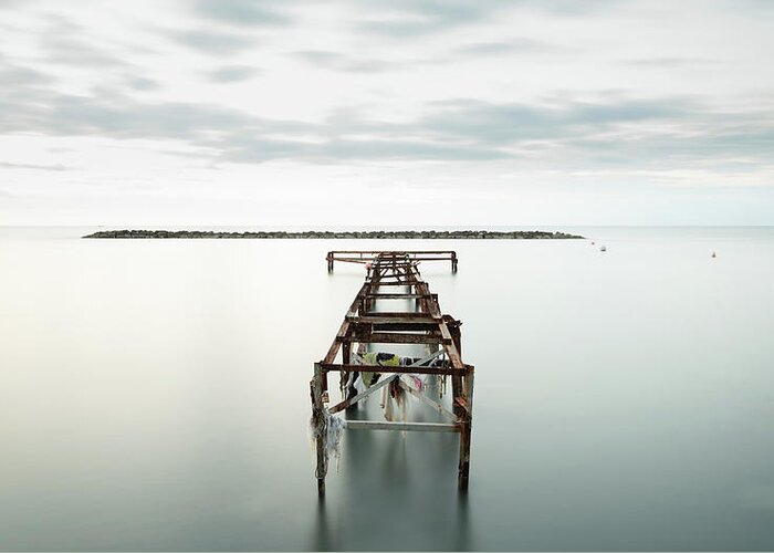 Jetty Greeting Card featuring the photograph Abandoned pier in the ocean. Long Exposure by Michalakis Ppalis