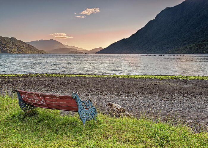 Chili Greeting Card featuring the photograph Bench with a peacefull view on the Hornopiren fjord on sunset by Henri Leduc