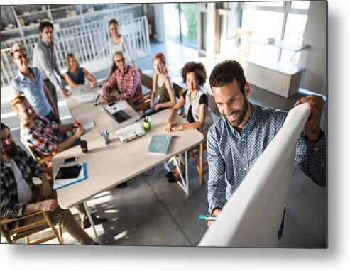 New Business Metal Print featuring the photograph Above view of happy entrepreneur explaining the business plan to his team on a presentation in the office. by Skynesher