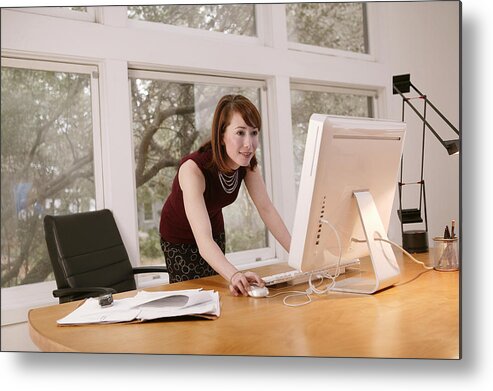 Working Metal Print featuring the photograph Businesswoman working at desktop computer by Comstock