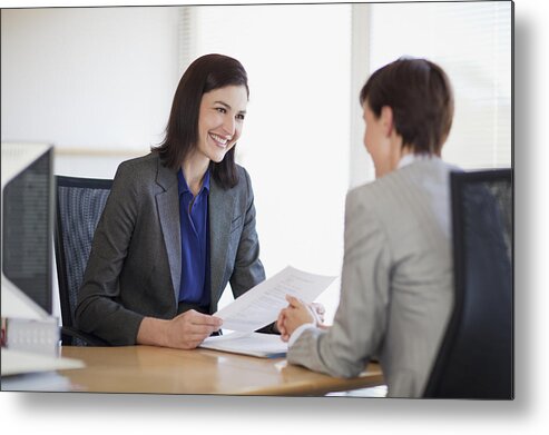 Working Metal Print featuring the photograph Businesswomen with paperwork talking face to face by Robert Daly