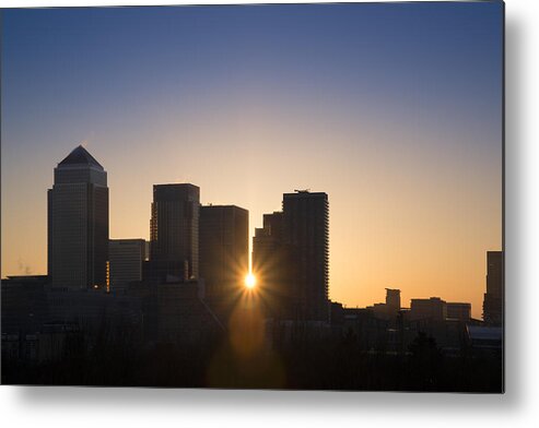 Landscape Metal Print featuring the photograph Canary Wharf skyline at sunrise with sun bursting through by Matthew Gibson