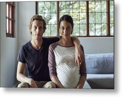 Heterosexual Couple Metal Print featuring the photograph Expectant couple sitting on sofa at home by Morsa Images