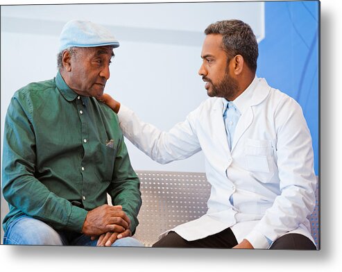 Expertise Metal Print featuring the photograph Male doctor consoling senior patient at hospital by Izusek