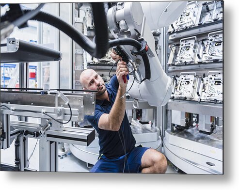 Expertise Metal Print featuring the photograph Man working at industrial robot in modern factory by Westend61