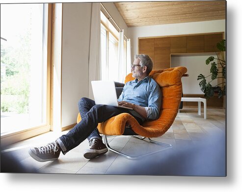 Internet Metal Print featuring the photograph Mature man using laptop in armchair by Westend61