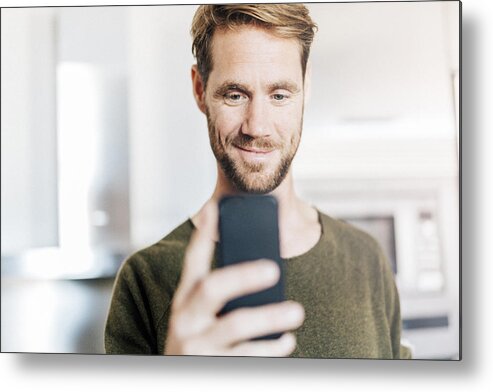 People Metal Print featuring the photograph Portrait of smiling man looking at cell phone by Westend61