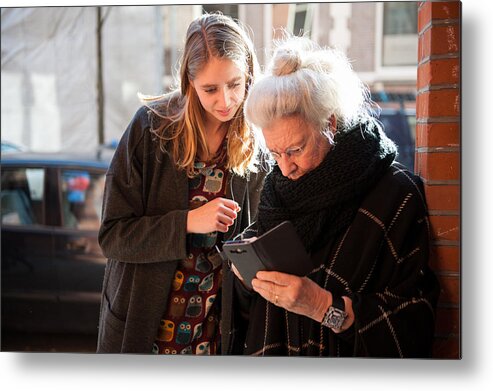 North Holland Metal Print featuring the photograph Senior lady and grandchild looking at smartphone by Lucy Lambriex