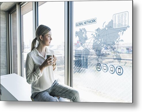 Expertise Metal Print featuring the photograph Young businesswoman looking at virtual world map at window pane in office by Westend61