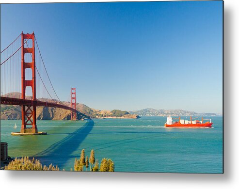 America Metal Print featuring the photograph An orange container ship with cranes passing under the Golden Ga by Jirawat Cheepsumol
