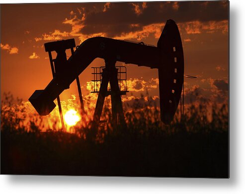 Oil Rig Metal Print featuring the photograph Oil rig pump jack silhouetted by setting sun by Mark Duffy