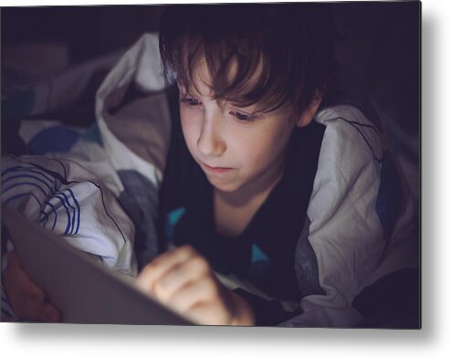 Working Metal Print featuring the photograph Boy lying in bed and playing at a digital tablet #1 by Da-kuk