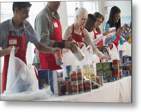 Asian And Indian Ethnicities Metal Print featuring the photograph Volunteers packing canned goods at food drive #1 by Jose Luis Pelaez Inc